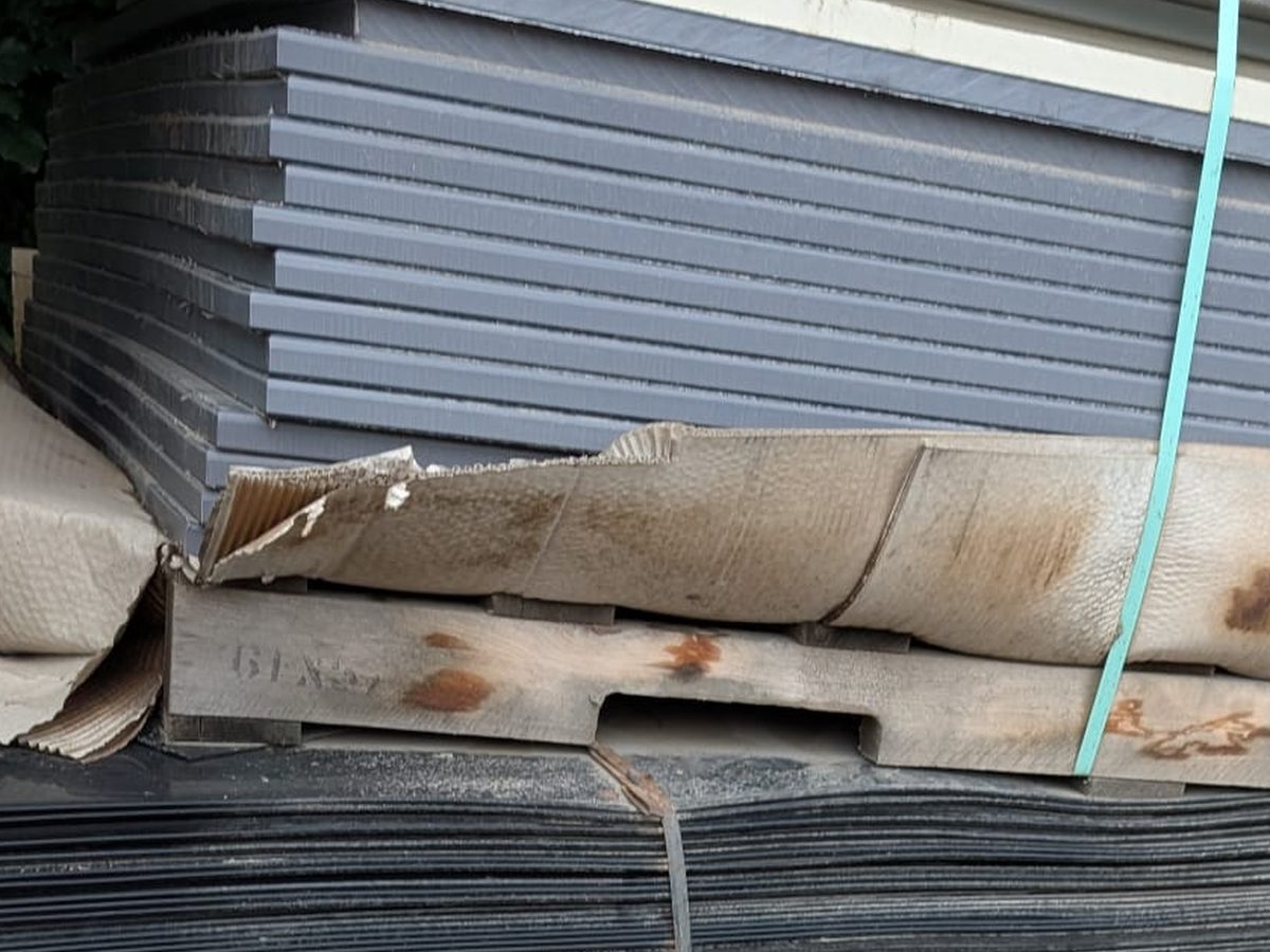 Grey rigid plastic sheets stacked and strapped on a pallet
